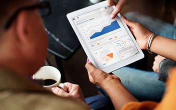 a woman holding a tablet device showing co-workers graphs and charts